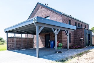 Doppelcarport mit Flachdach und grau gestrichener Holzkonstruktion an einem Backsteinhaus