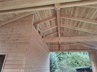 Innenansicht eines Doppelcarports mit sichtbaren Holzbalken und Holzverschalung