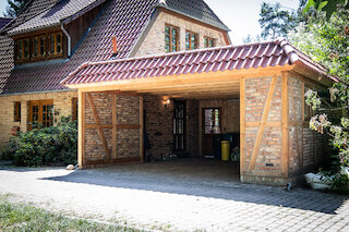 Holzcarport mit Ziegeldach an einem traditionellen Fachwerkhaus