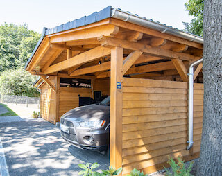 Holzcarport mit Satteldach und abgestelltem Auto
