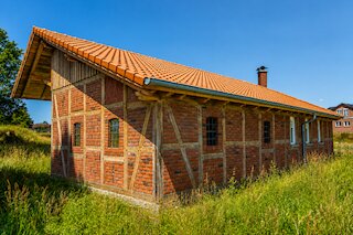 Historisches Fachwerkhaus mit rotem Ziegeldach und Backsteinfassade in ländlicher Umgebung