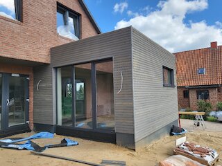 Moderner Holzanbau mit grauer Holzfassade während der Fertigstellung