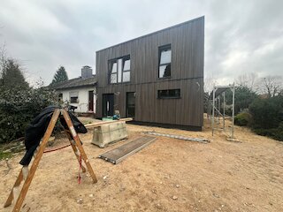 Zweigeschossiger Holzanbau mit dunkler Holzfassade im Bau