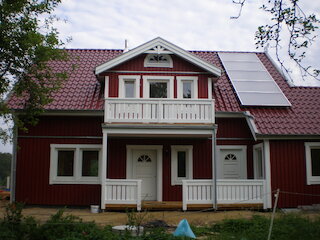 Rotes Holzhaus mit Balkon und überdachtem Eingang