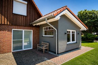 Moderner Hausanbau mit grauer Holzfassade, Satteldach und weißen Fenstern an einem bestehenden Wohnhaus